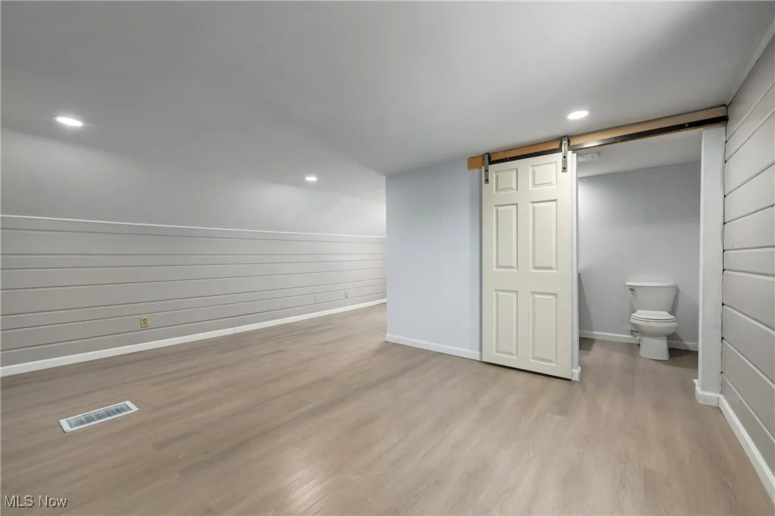 Below grade area featuring a barn door, wood finished floors, and recessed lighting