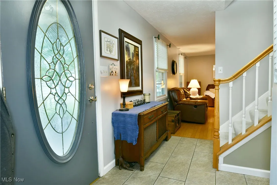 Entryway featuring light tile patterned flooring and stairway