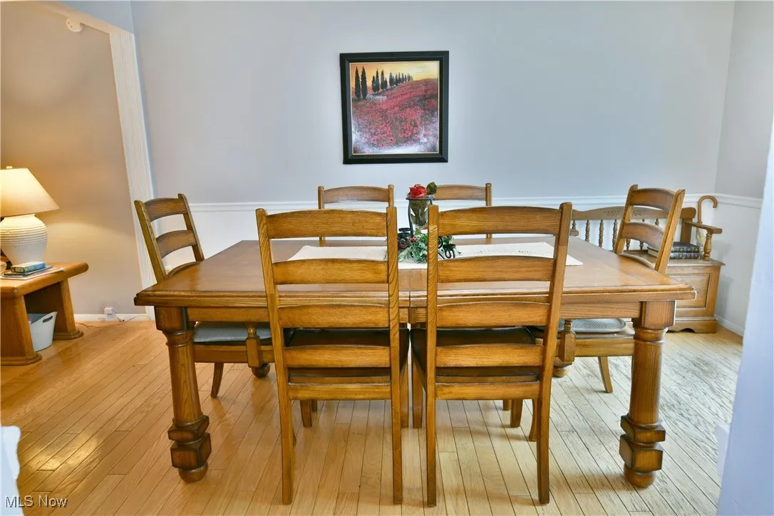 Dining area with light wood-type flooring and wainscoting