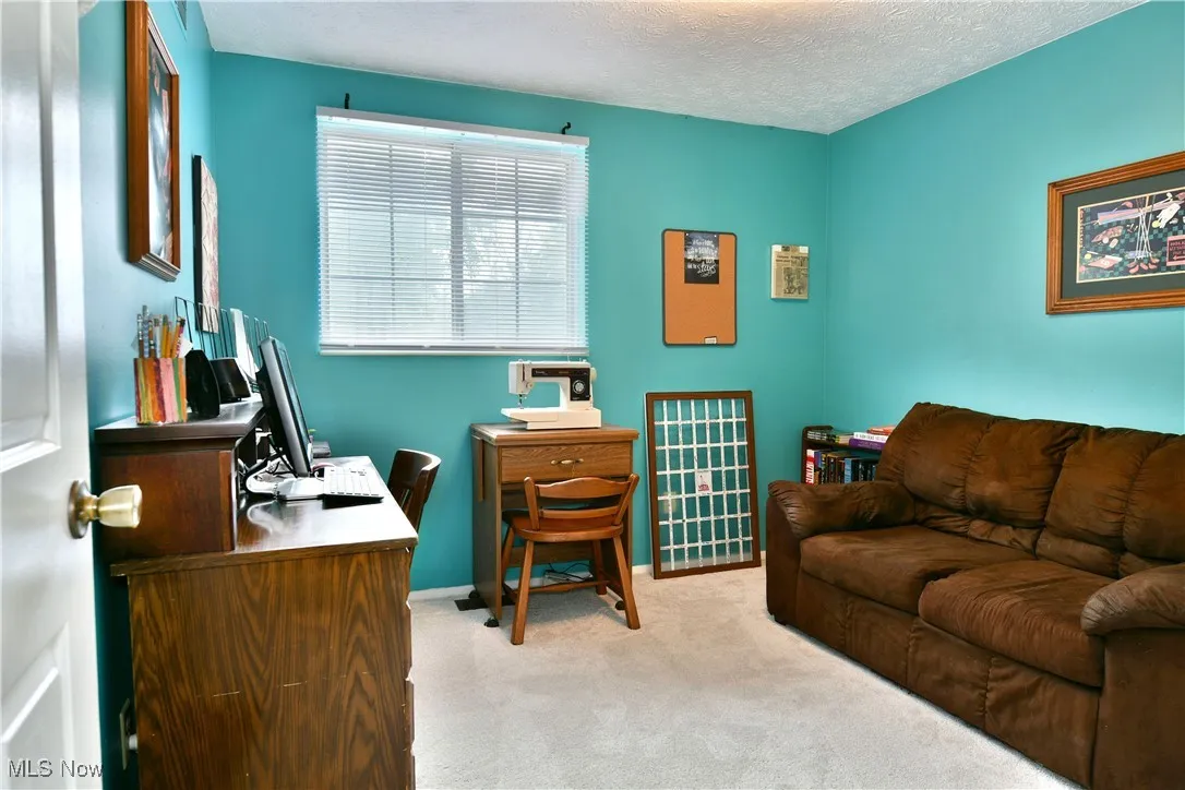 Carpeted home office with a textured ceiling and baseboards