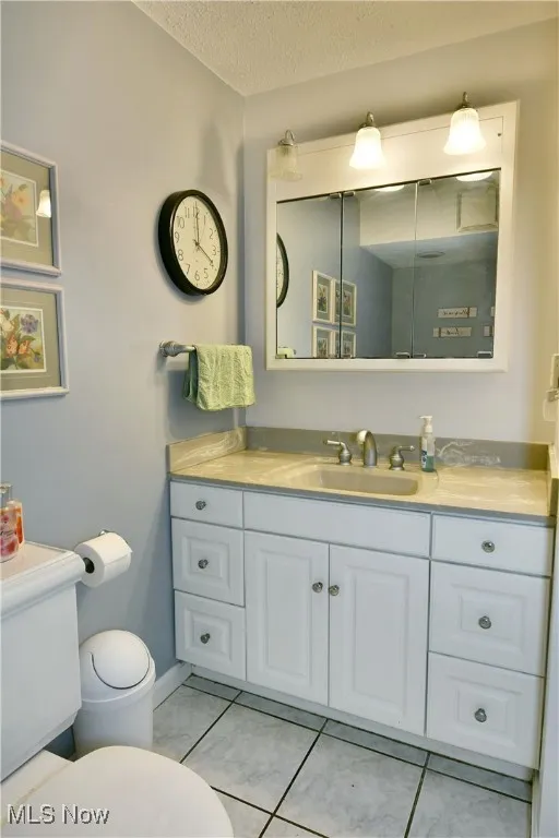 Bathroom featuring vanity, tile patterned flooring, and a textured ceiling