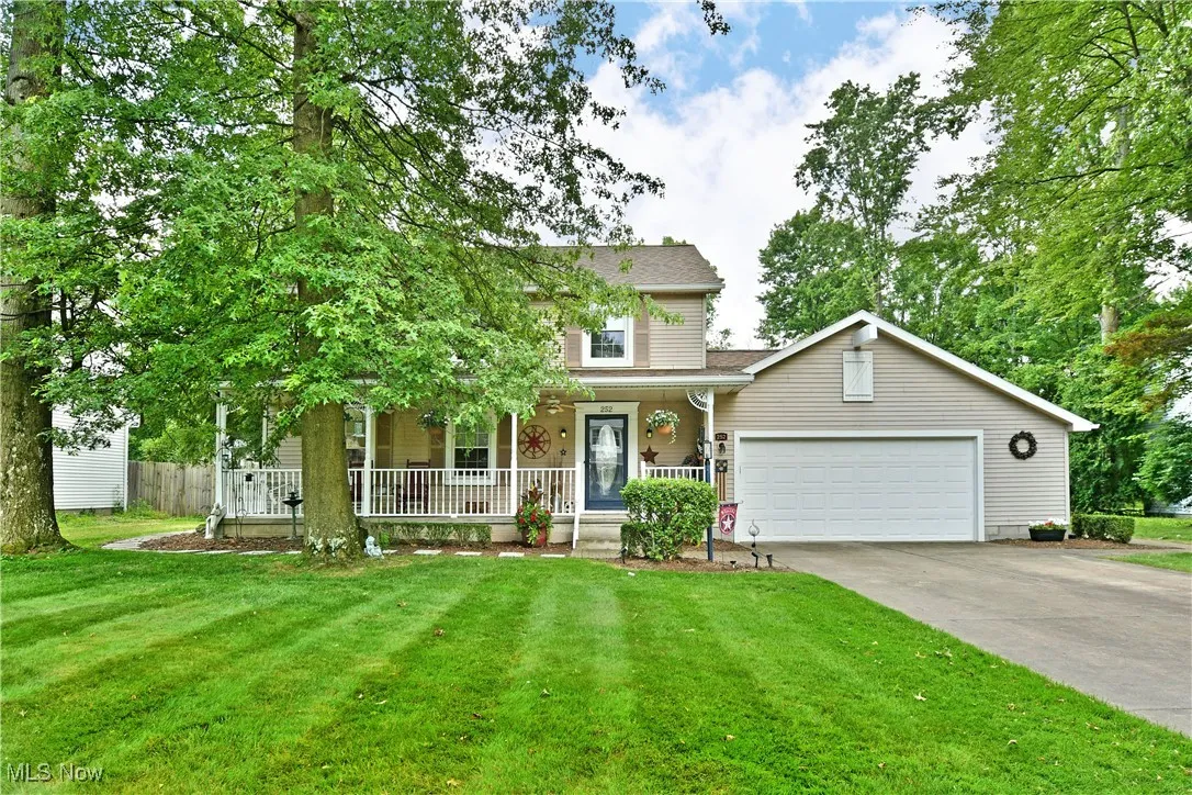 View of front of property with a porch, an attached garage, driveway, a front lawn, and a shingled roof