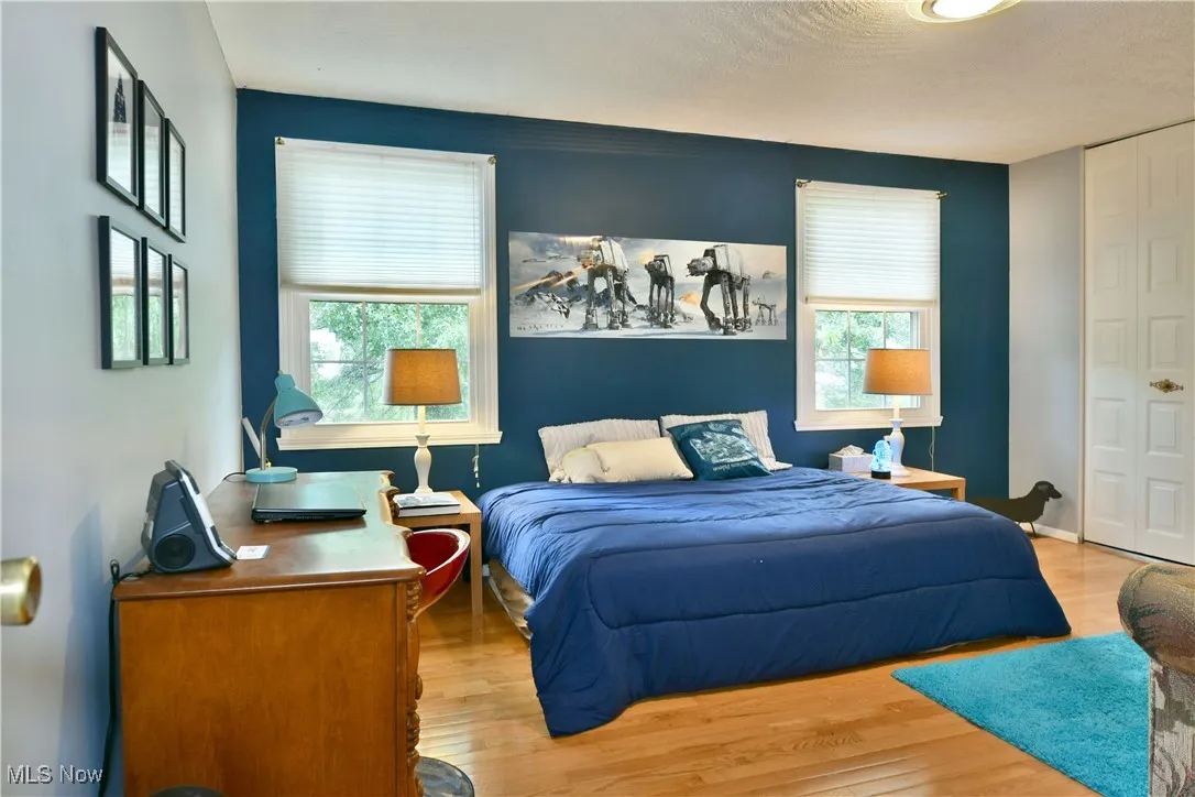 Bedroom with wood finished floors and multiple windows