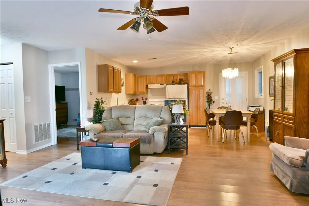 Living area with light wood finished floors, a ceiling fan, and a chandelier
