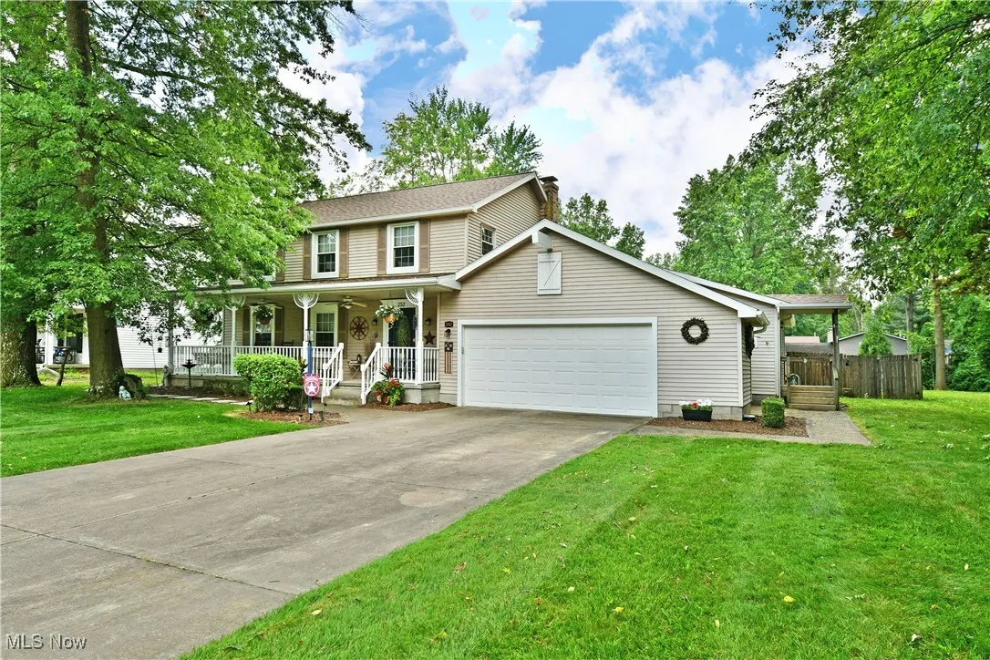 View of front of property with a porch, a garage, driveway, and a chimney