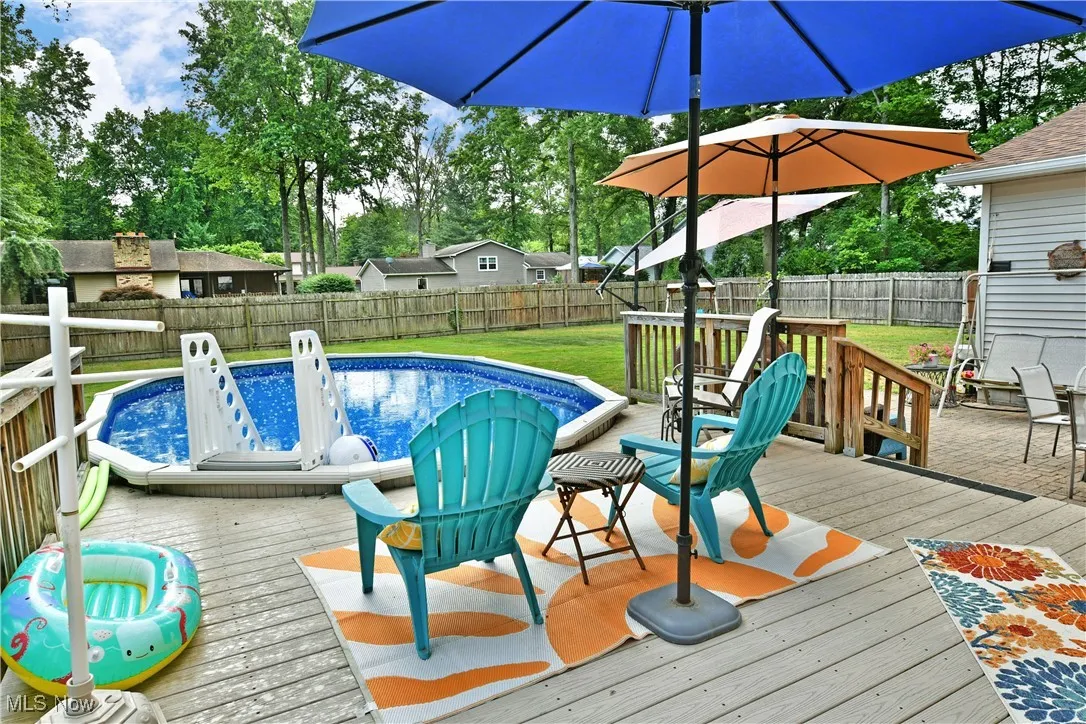 View of pool featuring a fenced backyard, a wooden deck, and view of scattered trees