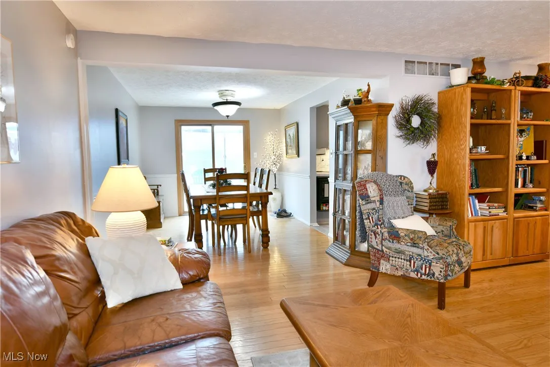 Living room with a textured ceiling, wainscoting, and wood finished floors