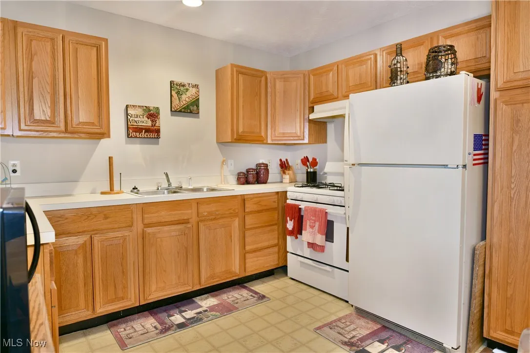 Kitchen with white appliances, extractor fan, light flooring, light countertops, and recessed lighting