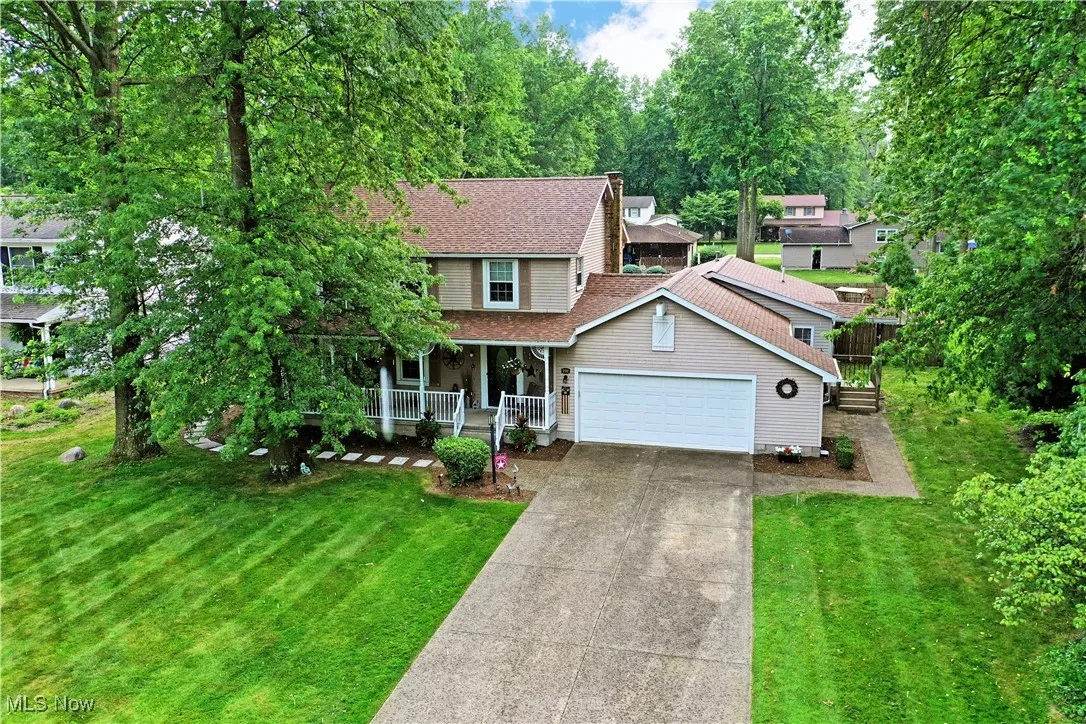 View of front of home with a porch, a garage, a front yard, and driveway