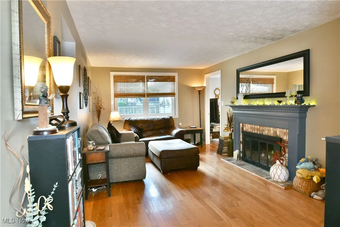 Living room featuring wood finished floors, a brick fireplace, and a textured ceiling