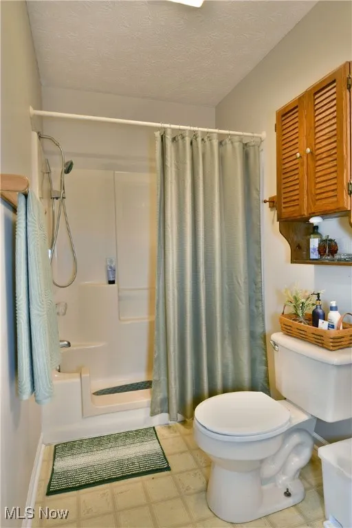 Bathroom featuring a textured ceiling, shower / tub combo, and tile patterned floors