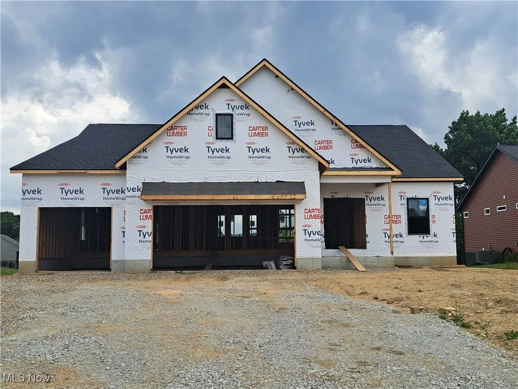 Unfinished property with gravel driveway and roof with shingles