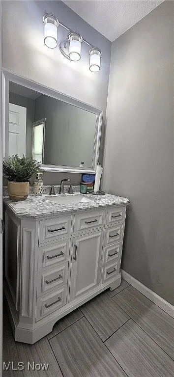 Bathroom with vanity, wood finished floors, and a textured ceiling