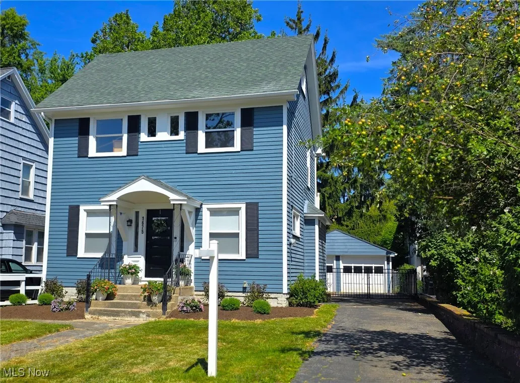 View of front of house with newer landscaping, fenced in backyard and large garage.
