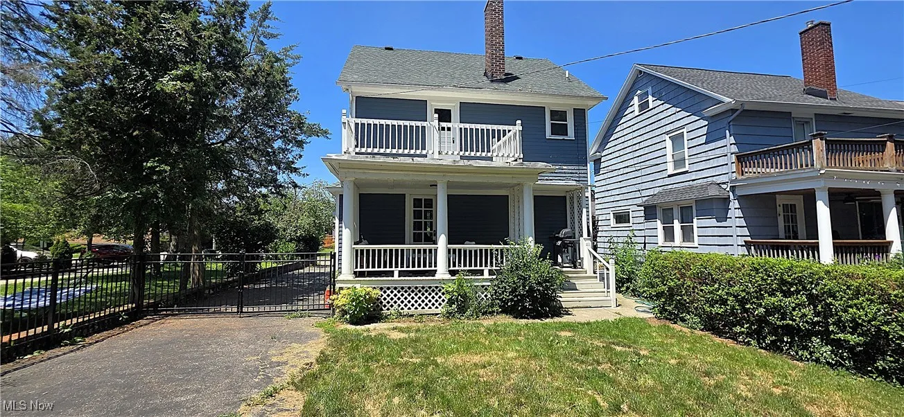 View of front of home featuring a balcony, covered porch, a chimney, and roof with shingles