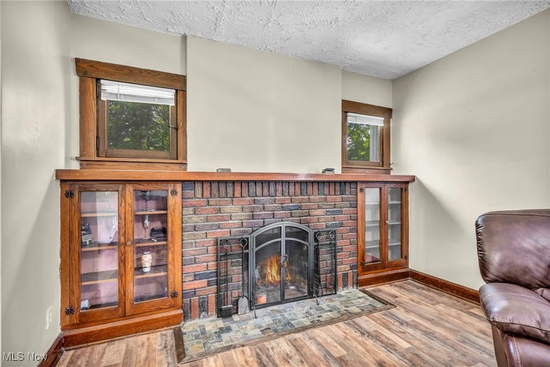 Living room featuring wood finished floors, a textured ceiling, and a fireplace