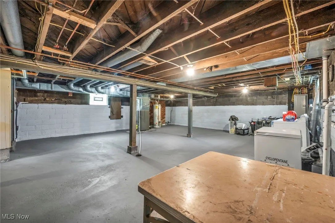 Below grade area featuring water heater, fridge, and electric panel
