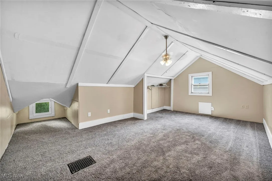 Bonus room with healthy amount of natural light, vaulted ceiling, and carpet floors