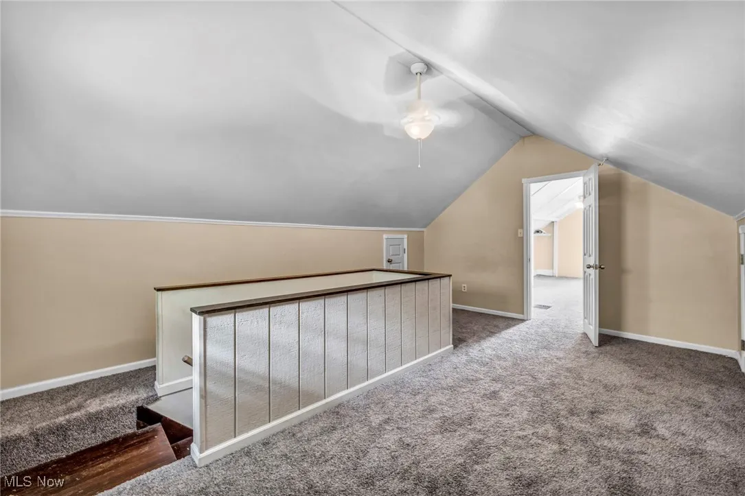 Additional living space featuring carpet floors, lofted ceiling, and a ceiling fan
