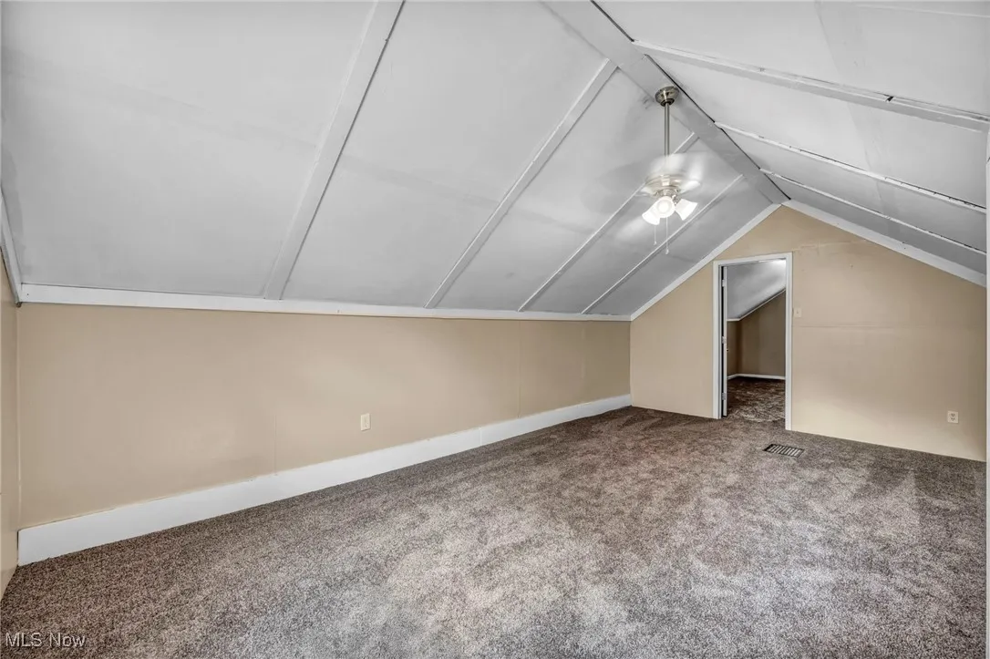 Additional living space featuring carpet, lofted ceiling, and a ceiling fan