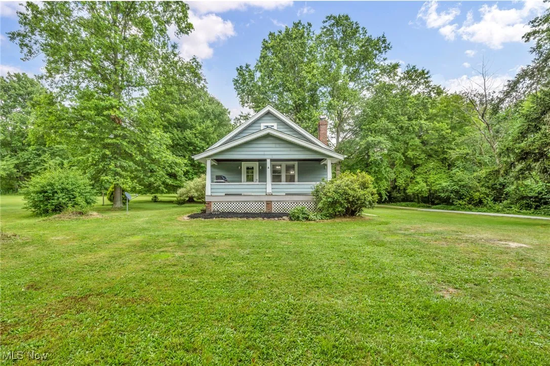 View of front of house with a front lawn, a porch, and a chimney