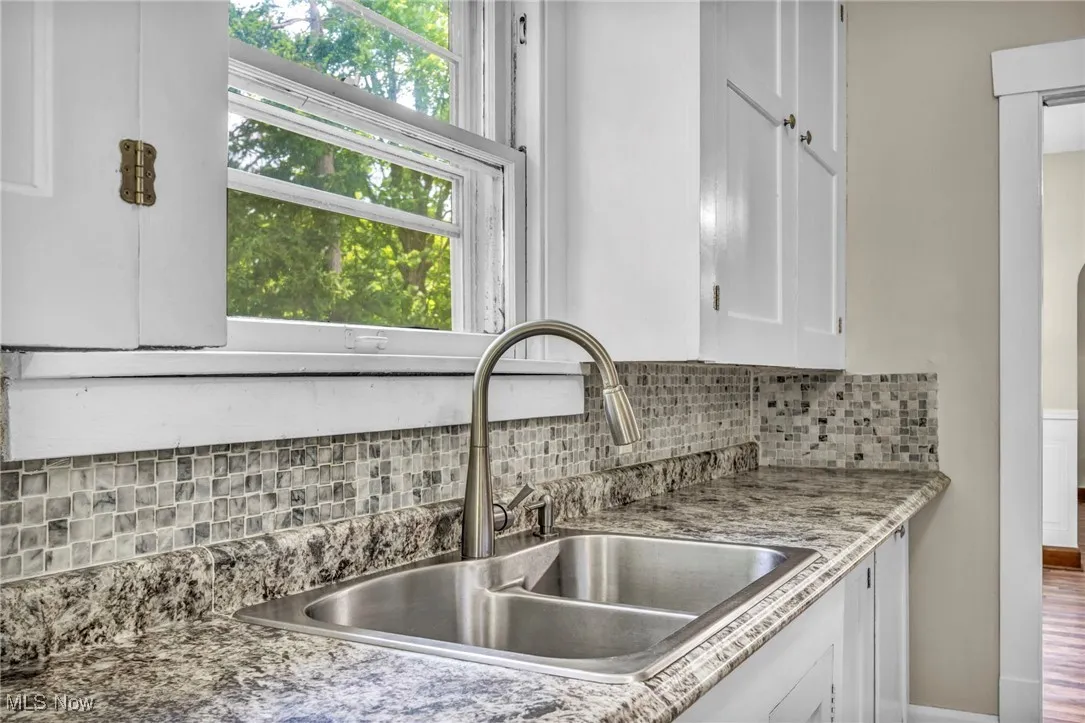 Kitchen with white cabinetry and decorative backsplash