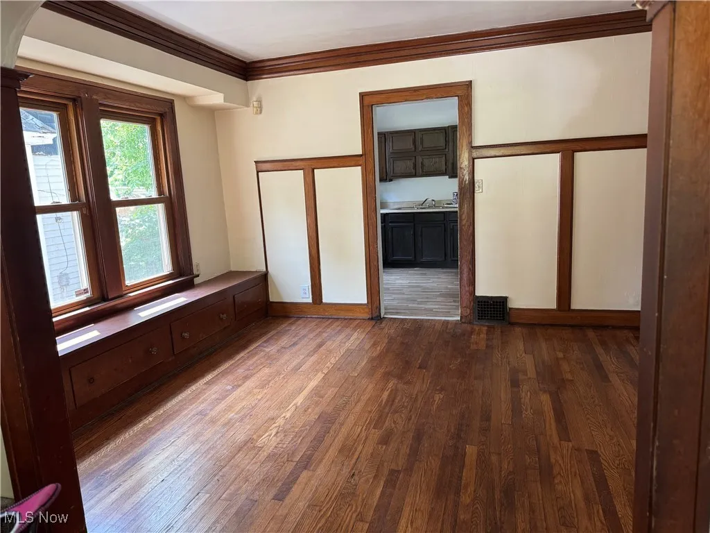 Unfurnished room with hardwood / wood-style flooring, ornamental molding, and arched walkways