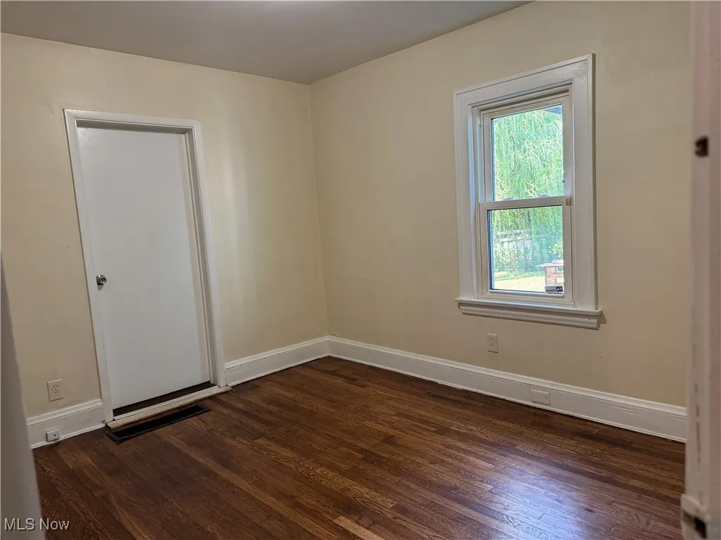 Unfurnished room with dark wood-type flooring and baseboards