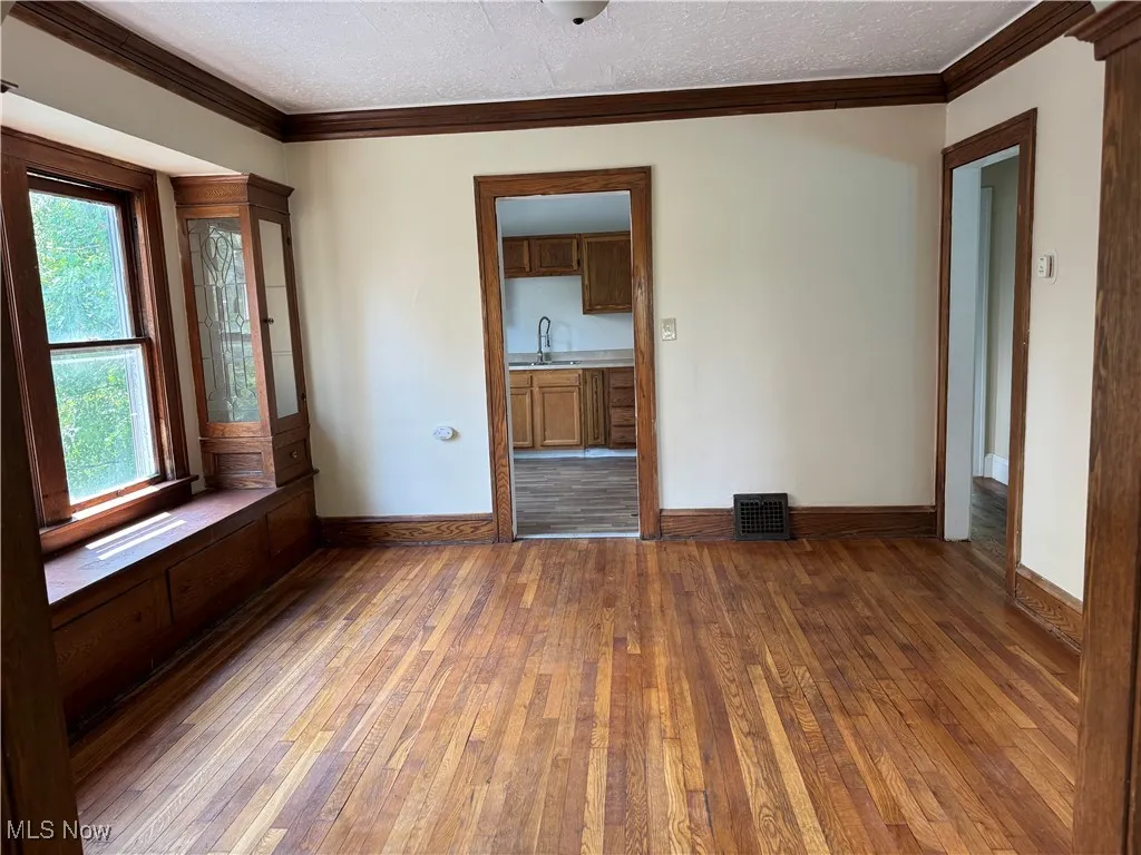Spare room featuring hardwood / wood-style floors, ornamental molding, and a textured ceiling