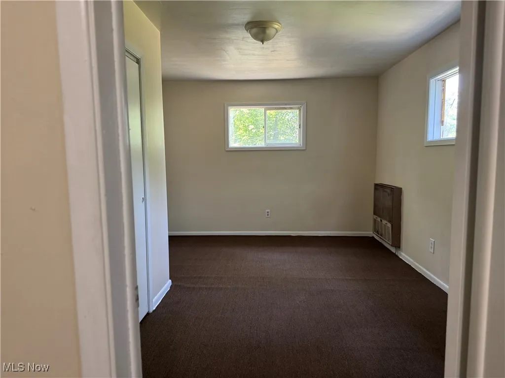Empty room with plenty of natural light and dark carpet