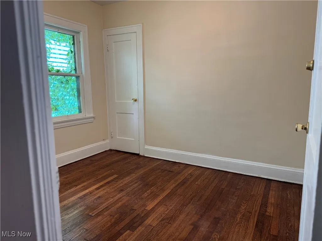 Spare room featuring dark wood-style floors and baseboards