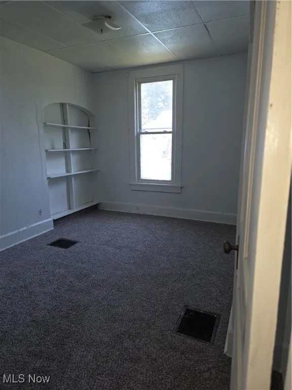 Empty room featuring carpet floors and a drop ceiling