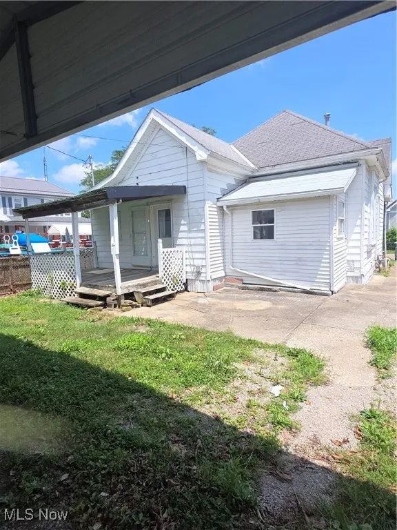 Back of property featuring a lawn and roof with shingles