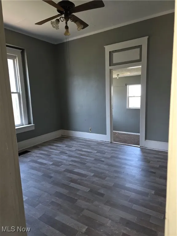 Unfurnished room featuring ceiling fan and dark wood-style flooring