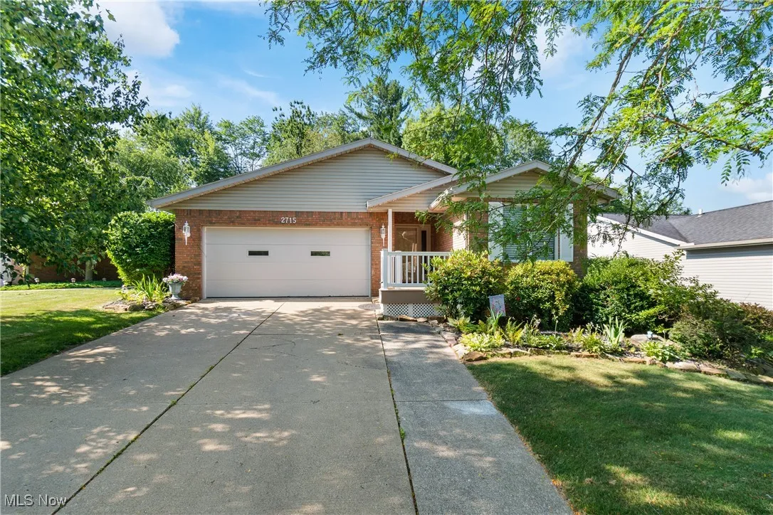 Ranch-style house featuring brick siding, a front yard, driveway, and an attached garage