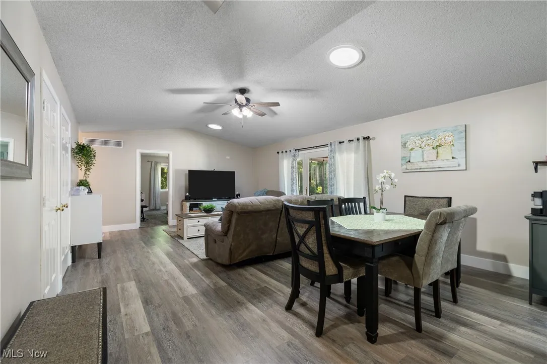 Dining room featuring wood finished floors, ceiling fan, lofted ceiling, and a textured ceiling