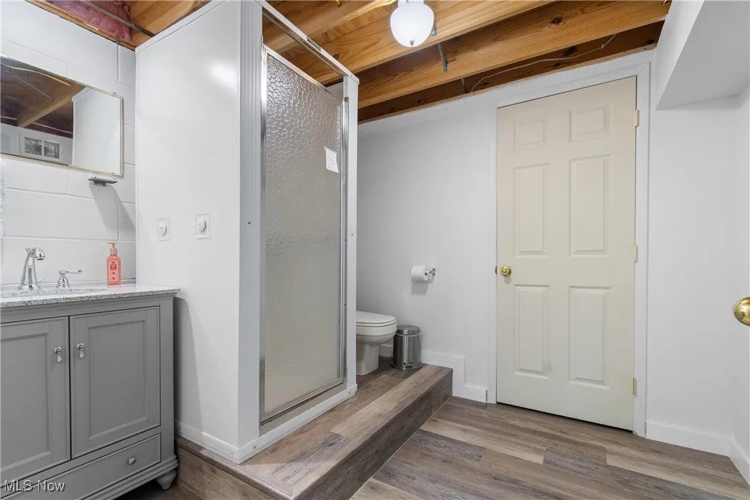 Bathroom with vanity, a stall shower, and wood finished floors