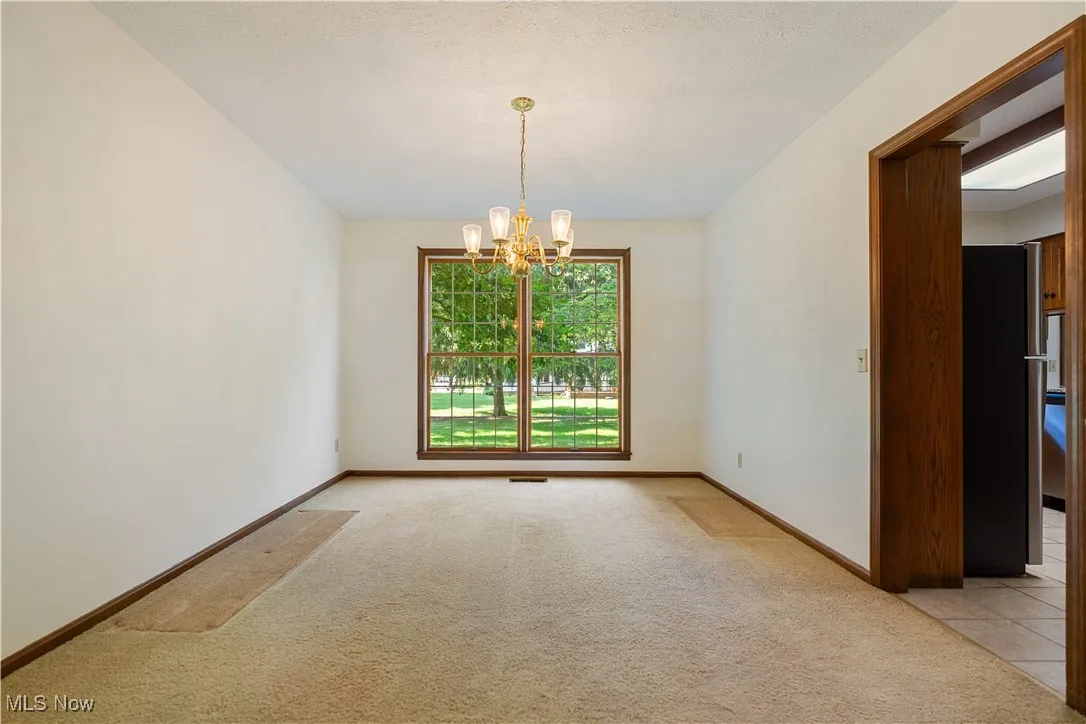 Spare room featuring light carpet and a chandelier
