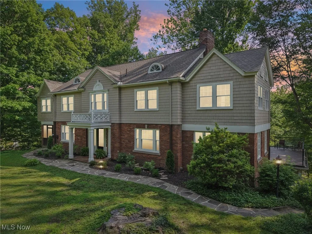 View of front of home with a front lawn, a chimney, a shingled roof, and brick siding