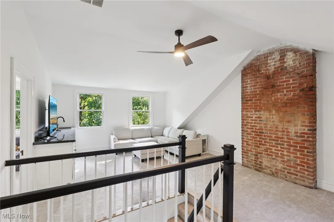 Living room featuring a ceiling fan, carpet, and vaulted ceiling