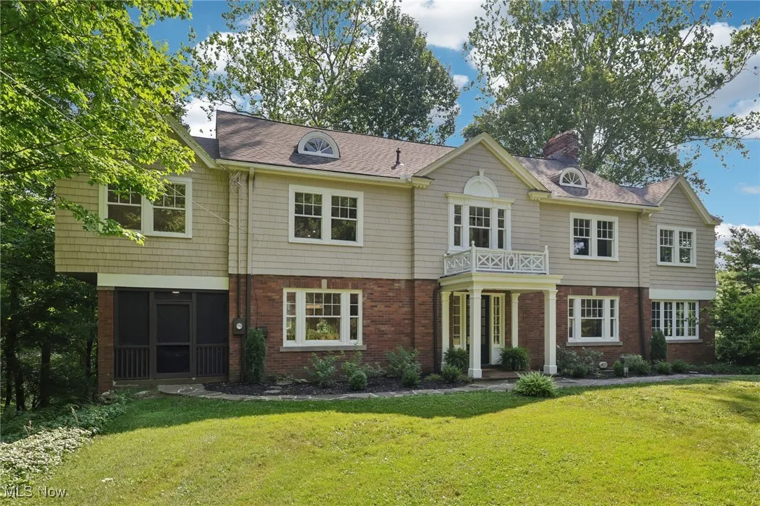 View of front of property with a front lawn, brick siding, and a chimney