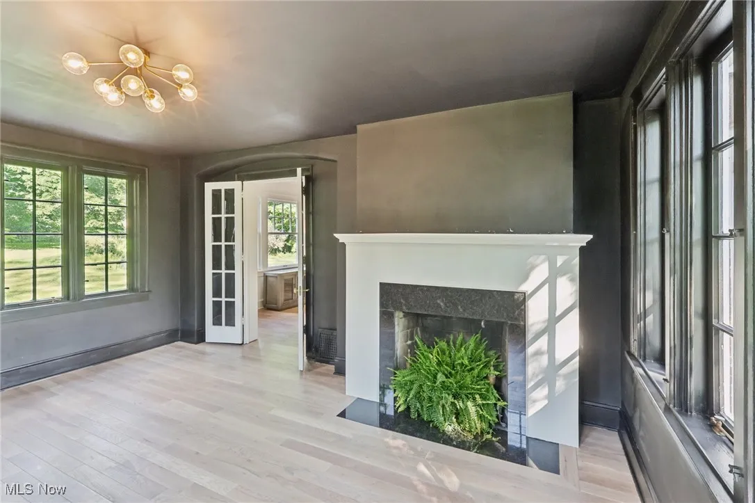 Unfurnished living room featuring wood finished floors, a chandelier, a fireplace with flush hearth, and plenty of natural light
