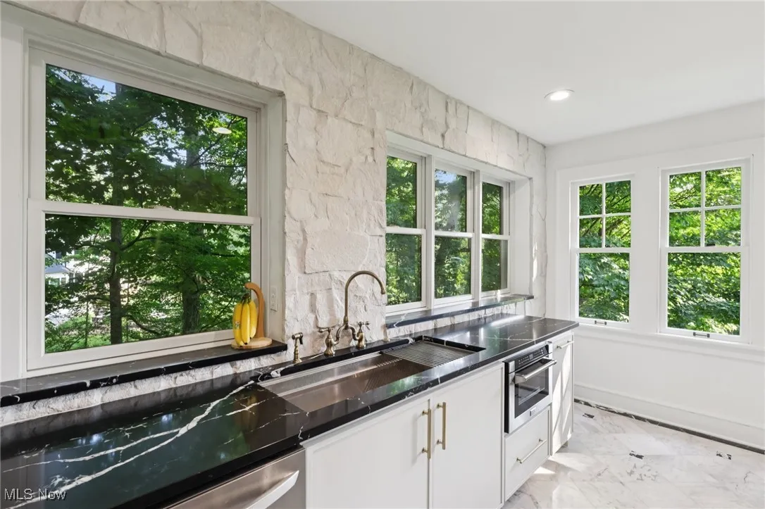 Kitchen featuring white cabinetry, light marble finish floors, dark countertops, dishwasher, and recessed lighting