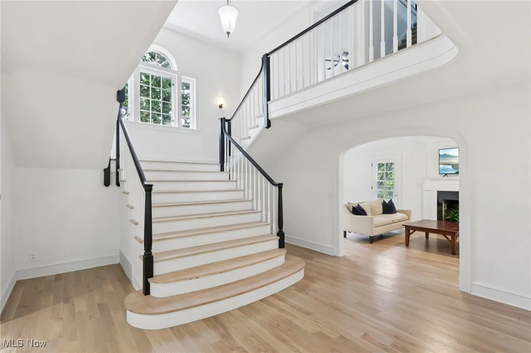 Staircase featuring plenty of natural light, wood finished floors, a fireplace, and arched walkways