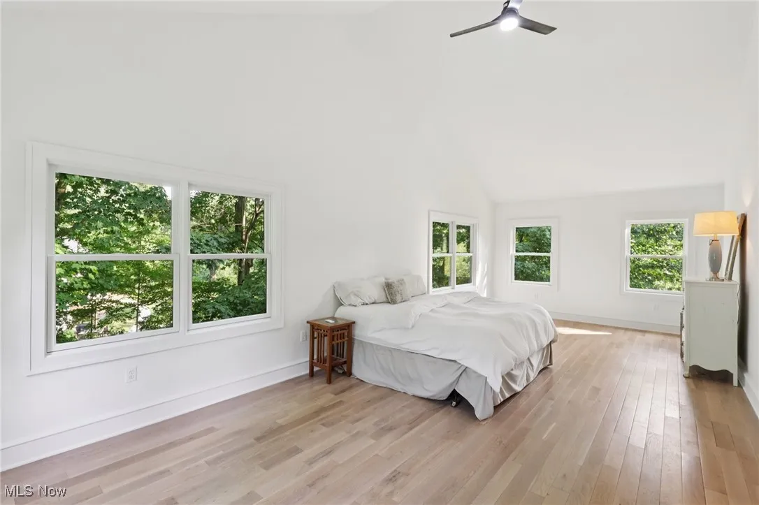 Bedroom with light wood-style flooring, high vaulted ceiling, and a ceiling fan