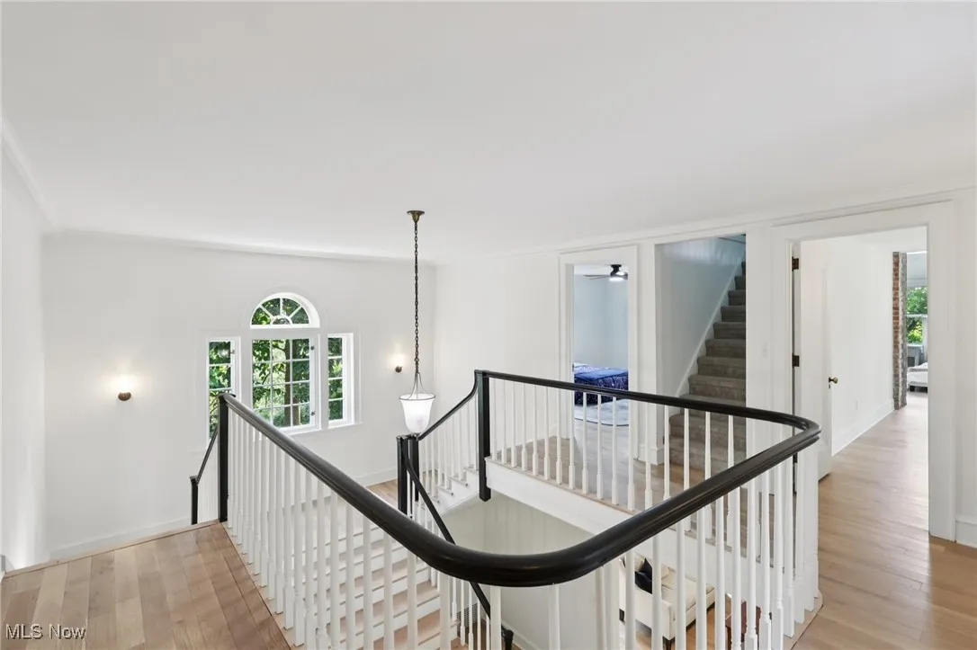 Hall featuring an upstairs landing, healthy amount of natural light, light wood-style flooring, and crown molding