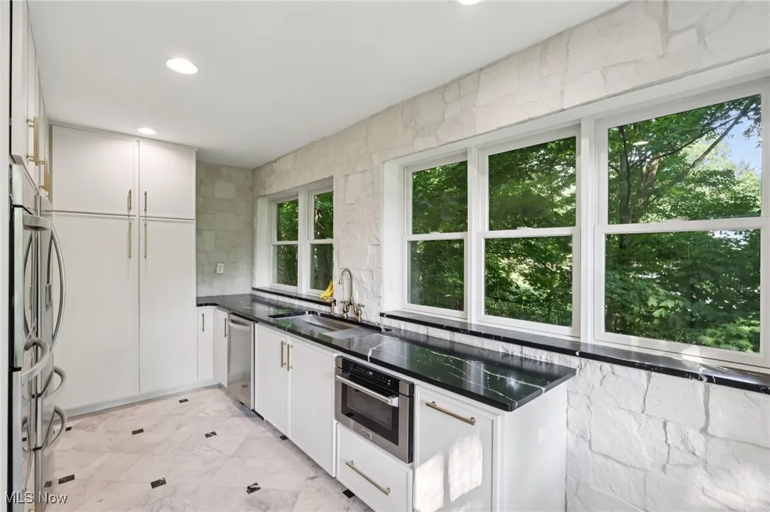 Kitchen featuring stainless steel appliances, white cabinets, dark countertops, recessed lighting, and backsplash