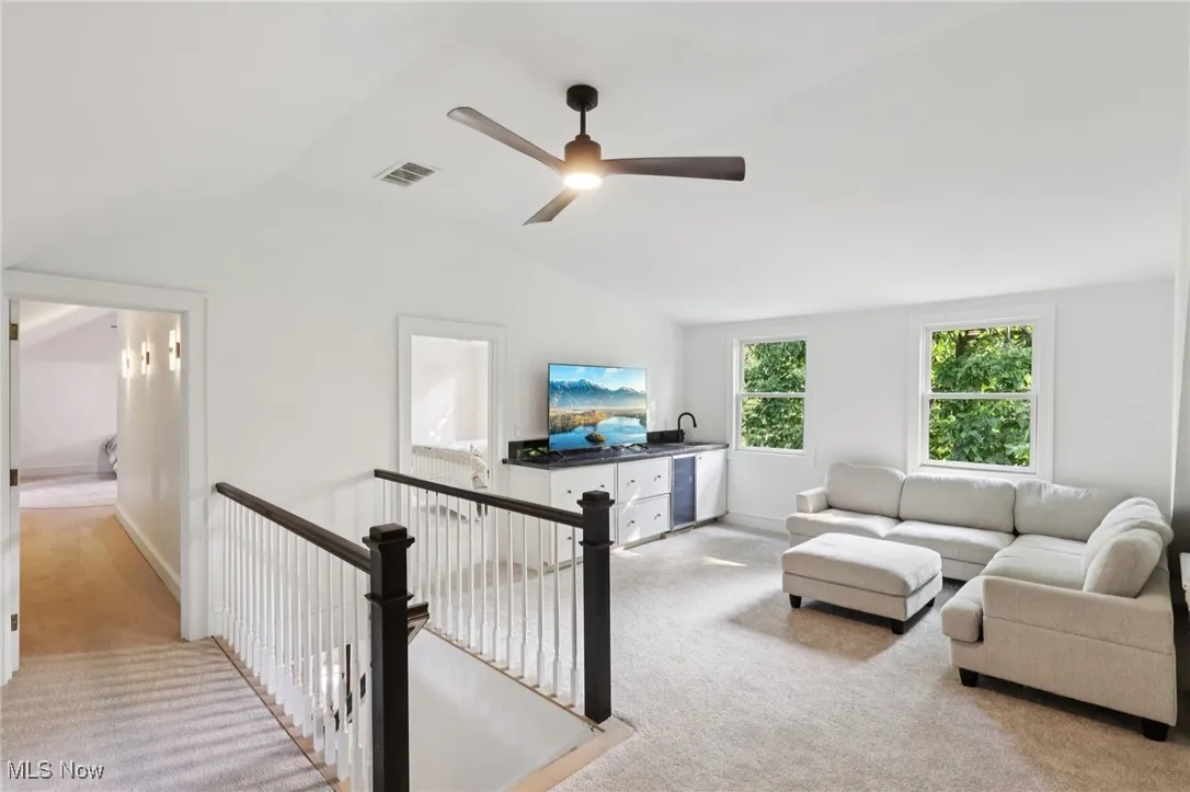 Carpeted living area with vaulted ceiling and a ceiling fan