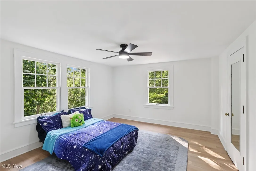 Bedroom featuring multiple windows, wood finished floors, and ceiling fan