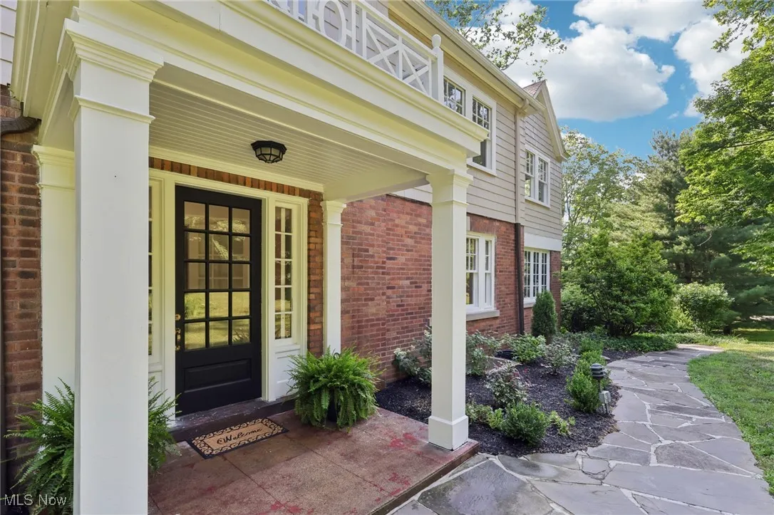 Entrance to property featuring brick siding and covered porch